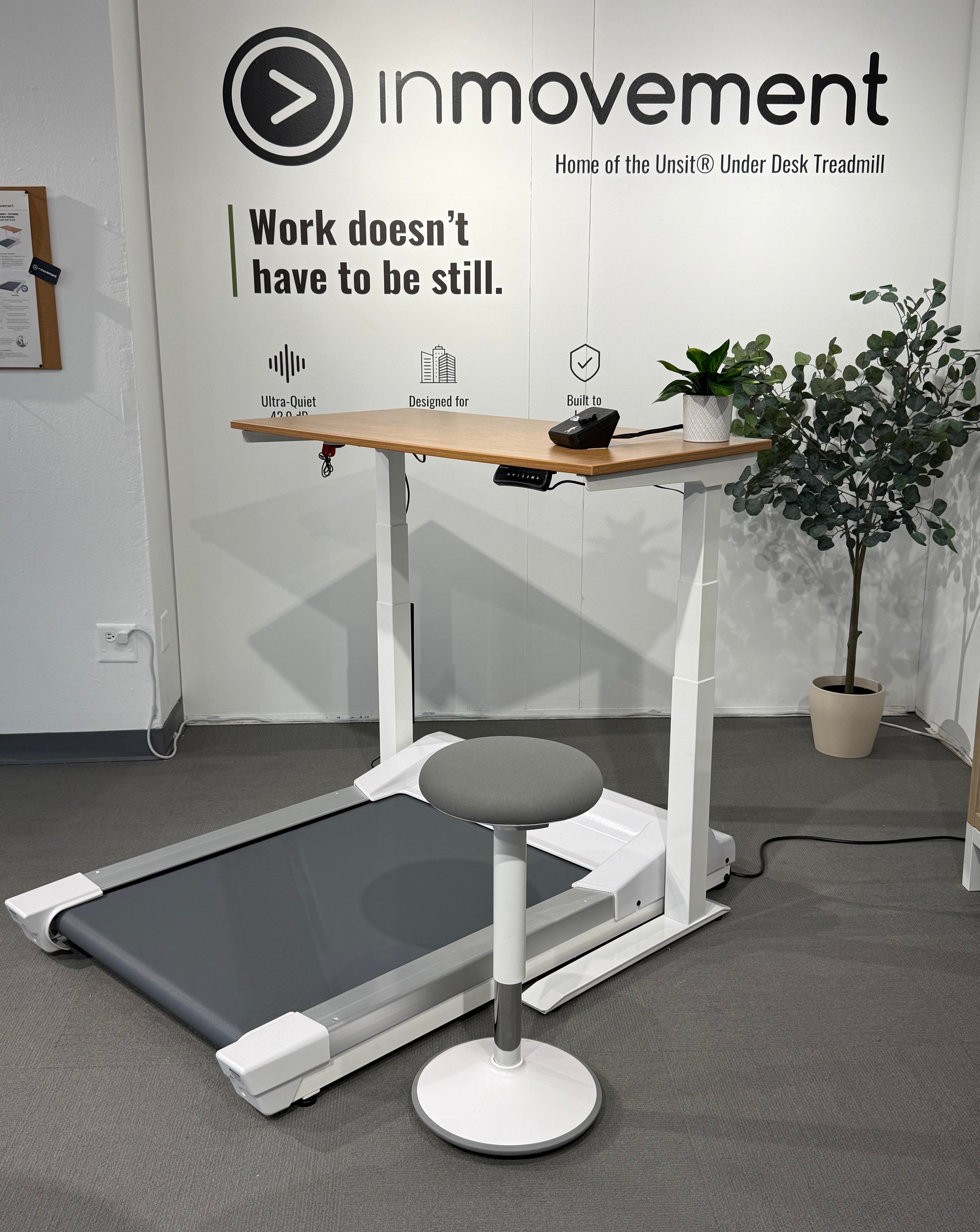 Under desk treadmill with a standing stool in an office setting, featuring the 'inmovement' brand.