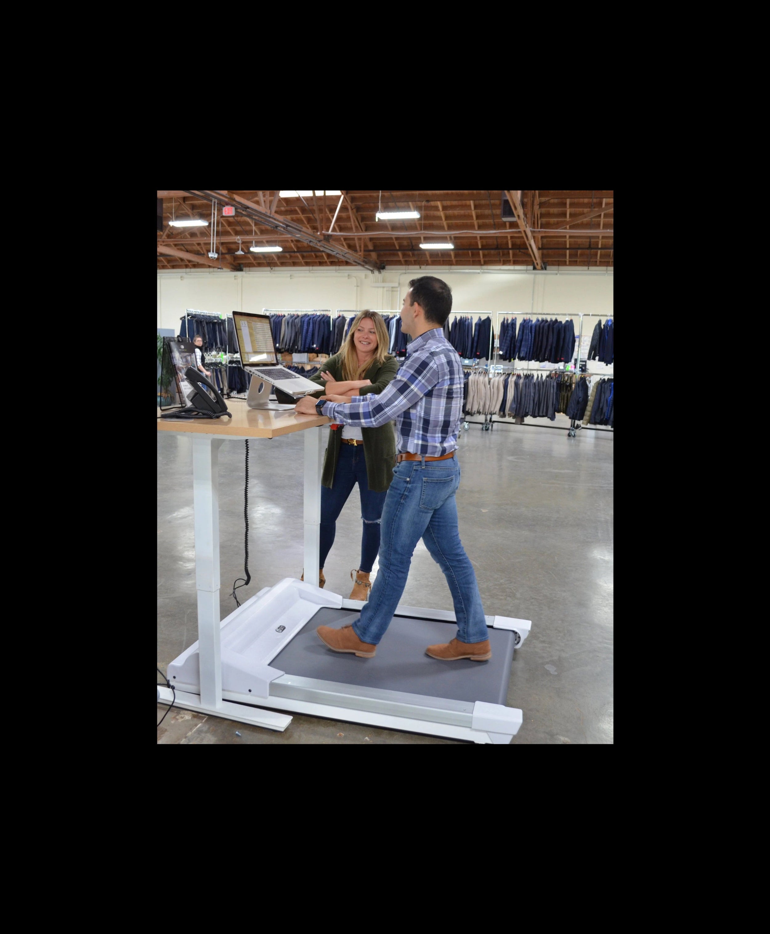 Man using an Unsit treadmill in a clothing store with a woman standing nearby.