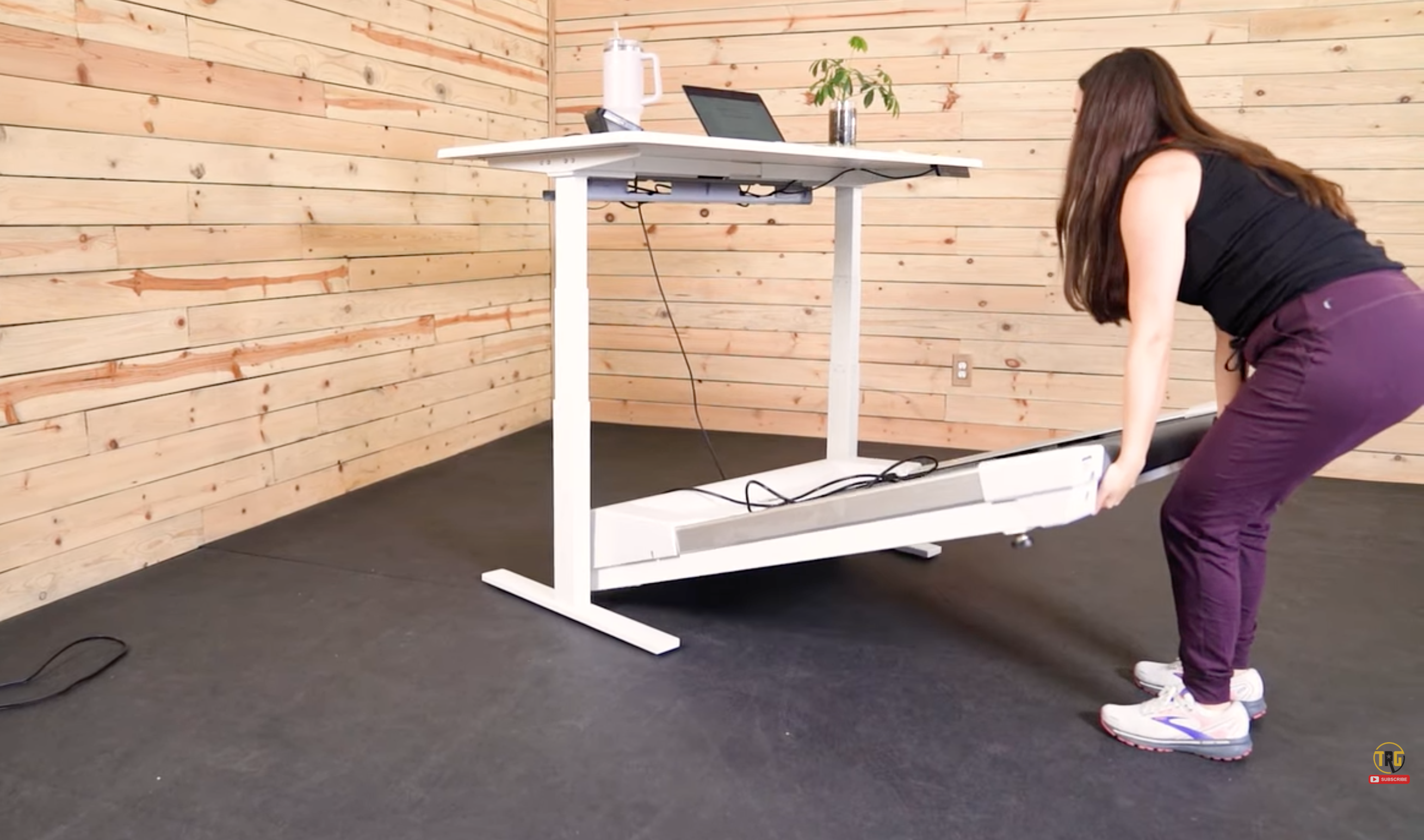 A woman slides the Unsit treadmill underneath her standing desk