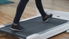 Blond woman walks on an Unsit Treadmill in a clean and bright open office space with hardwood floors